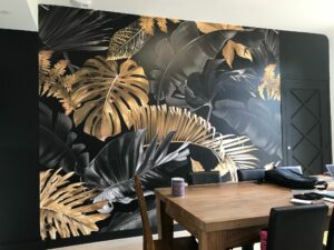 Fresque murale feuillage en or et noir pour salle à manger. Design élégant et sophistiqué. Prix : 3 000 € TTC.